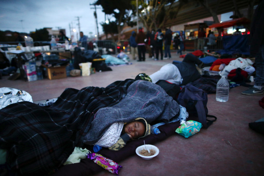 Members of a caravan of migrants from Central America sleep near the San Ysidro checkpoint after a small group of fellow migrants entered the United States border and customs facility, where they are expected to apply for asylum, in Tijuana